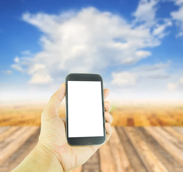 Hand holding smart phone on blurred wooden table background — Stock Photo, Image