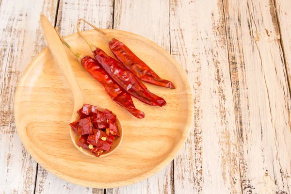 Dried chili peppers in wooden plate on wooden background — Stock Photo, Image