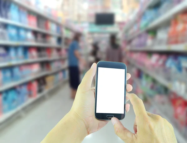 Рука тримає смартфон з розмитим фоном супермаркету — стокове фото
