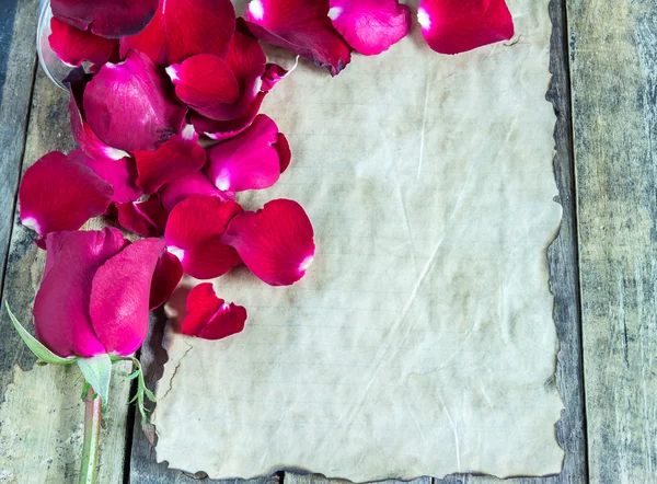 Νέο κόκκινο τριαντάφυλλο και παλιό χαρτί σε ξύλινα φόντο. — Φωτογραφία Αρχείου