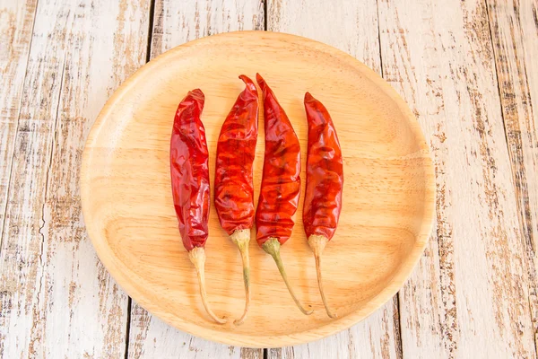 Dried chili peppers in wooden plate on wooden background — Stock Photo, Image