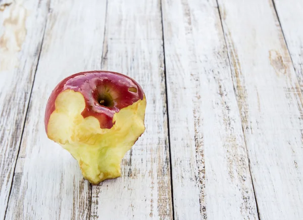 Uma maçã mordida no fundo de madeira branco — Fotografia de Stock