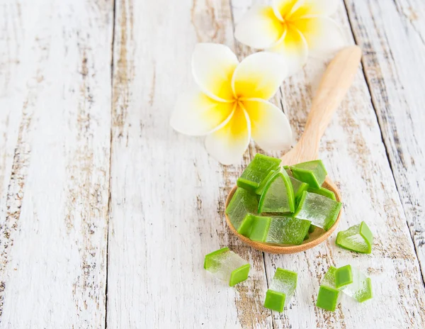 Aloe vera em colher de madeira e flor de frangipani em madeira branca — Fotografia de Stock