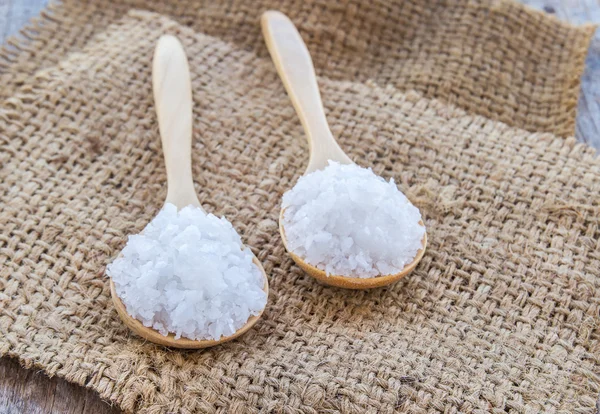 Sea salt in wooden spoon on burlap sack — Stock Photo, Image