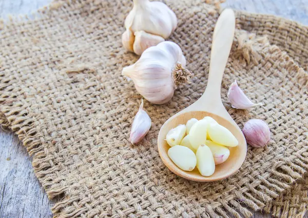 Knoflook op jute zak op houten achtergrond — Stockfoto