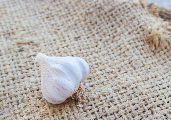 Knoflook op jute zak op houten achtergrond — Stockfoto