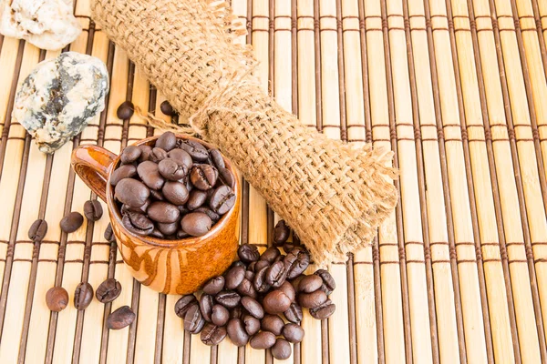 Granos de café con saco de arpillera sobre fondo de madera — Foto de Stock