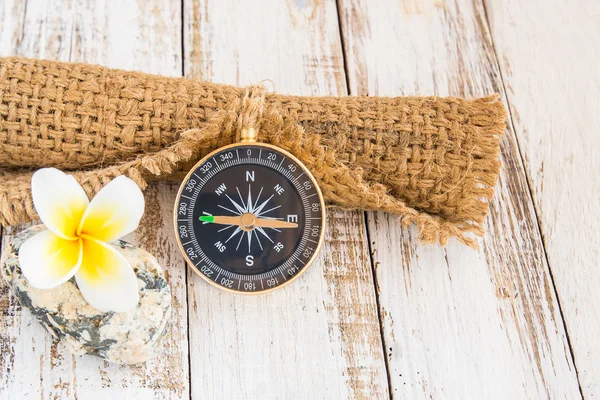 Close up compass and burlap sack on wooden background — Stock Photo, Image