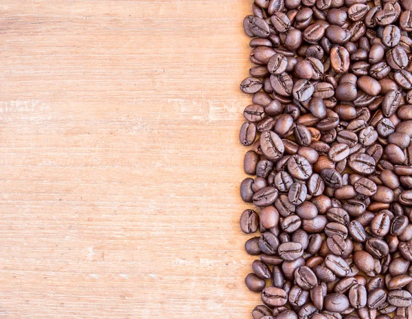 Granos de café sobre fondo de mesa de madera — Foto de Stock