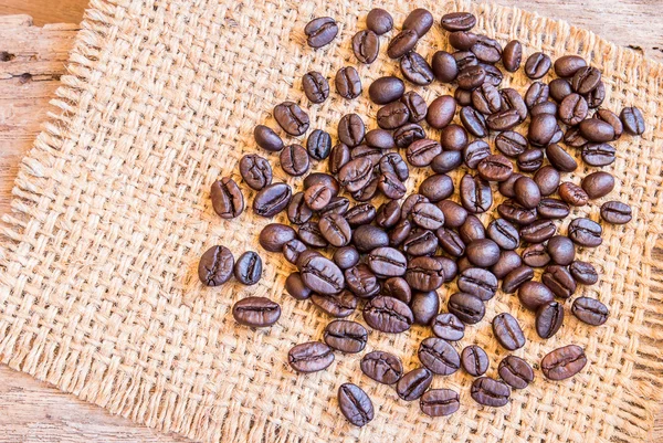 Roasted coffee beans on burlap sack — Stock Photo, Image