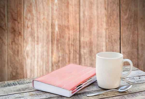 Notebook and coffee cup on wood table with blurred background — Stock Photo, Image