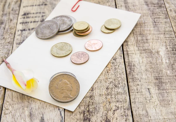 Moneda y flor sobre papel blanco sobre mesa de madera —  Fotos de Stock
