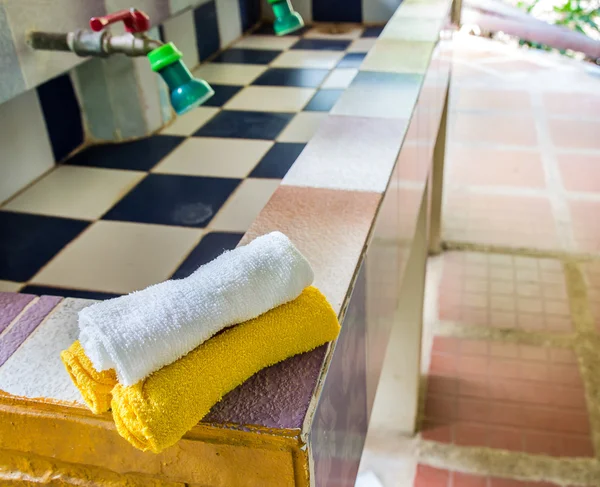 Toalhas brancas e amarelas na pia no banheiro — Fotografia de Stock