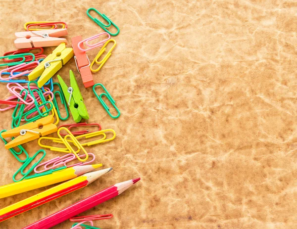 Colorful pencil and paperclips on old paper background — Stock Photo, Image
