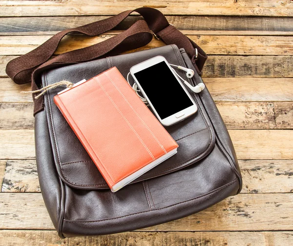 Brun läderväska, notebook, skarp telefonerna och hörlurar på trä — Stockfoto