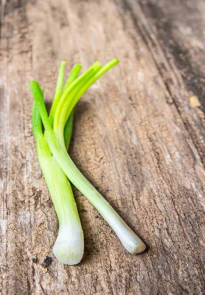 Oignons verts frais sur vieux fond en bois — Photo