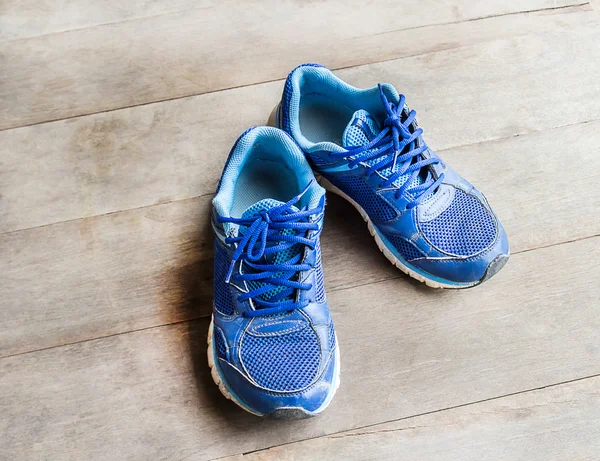 Sapatos de corrida azuis colocados em um piso de madeira — Fotografia de Stock