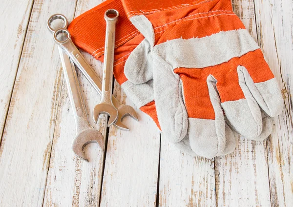 Leather work gloves and wrench on wooden table — Stock Photo, Image