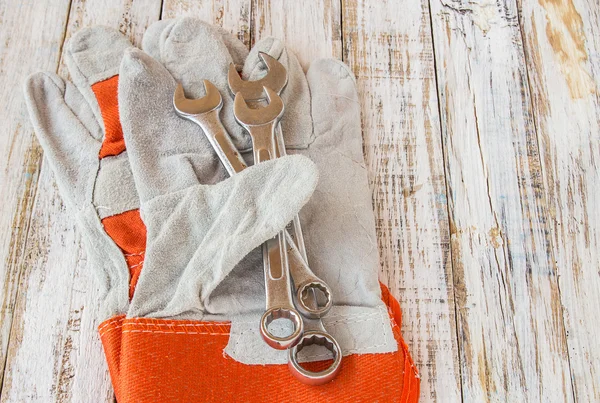 Leather work gloves and wrench on wooden table — Stock Photo, Image