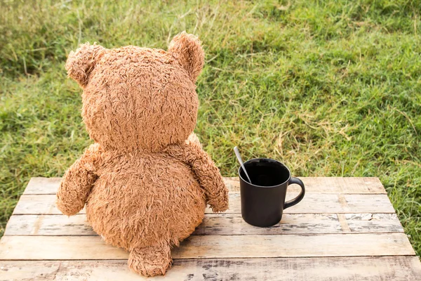 Ours en peluche assis à l'arrière et tasse à café sur une table en bois . — Photo