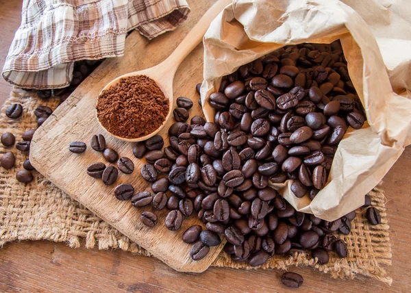 Black coffee beans in paper bag on wooden table — Stock Photo, Image