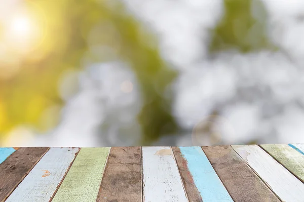 Lege houten dektafel met loof bokeh achtergrond — Stockfoto