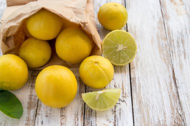 Freshly lemons in paper bag on white wooden table clipart