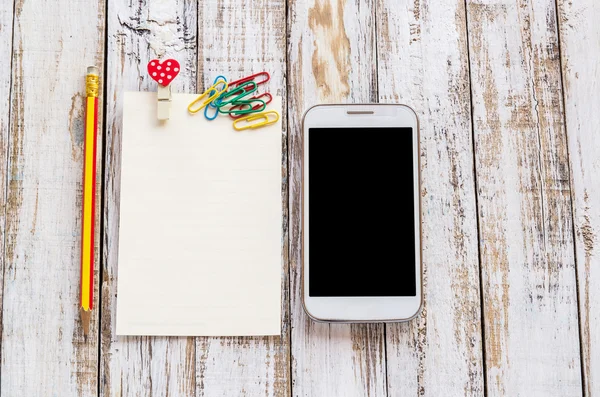 Papier en slimme telefoon op witte houten tafel — Stockfoto