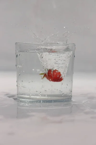 Mała Czerwona Truskawka Wpada Szklanki Pełnej Wody Białym Gruncie — Zdjęcie stockowe