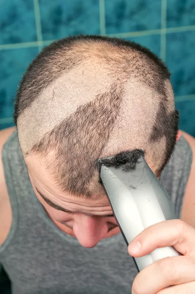 man shaves his head