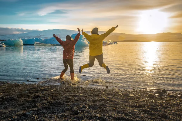 日落时在冰岛的Jokulsarlon冰川泻湖跳着的两个女孩 — 图库照片