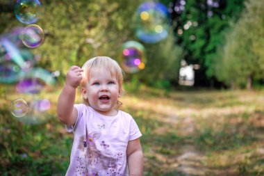 Mutlu küçük kız sabun köpüklerine bakıyor.