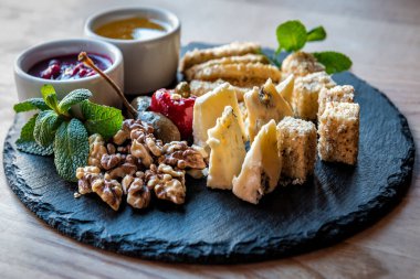 Fındık, sos ve yeşil nane yapraklarıyla dilimlenmiş farklı peynirler.