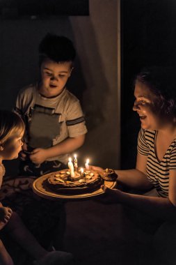 Çocuk doğum günü pastasındaki mumları üflüyor.