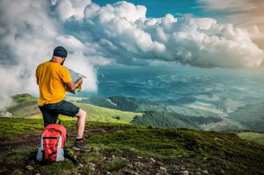 Karpatya dağlarında ve fırtınalı bulutlarda haritası olan bir turist. Seyahat ve tatil teması