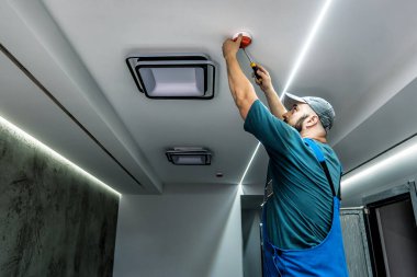 Profesyonel mavi tulum ustası yangın alarmını kuruyor ya da onarıyor