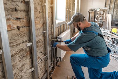 Profesyonel tesisatçı iş başında. Su ısıtma radyatörü kuruluyor