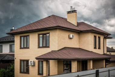 Fırtınalı gökyüzünün altında yeni çatısı olan özel tuğla ev.