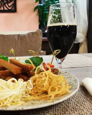 Bir bardak koyu bira ve tabakta atıştırmalık