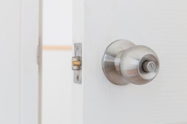 Detail of a metallic knob on white door clipart