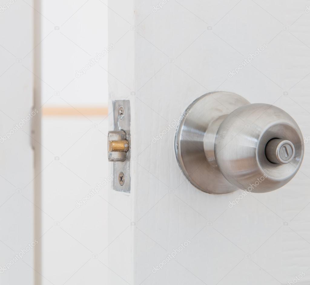 Detail of a metallic knob on white door