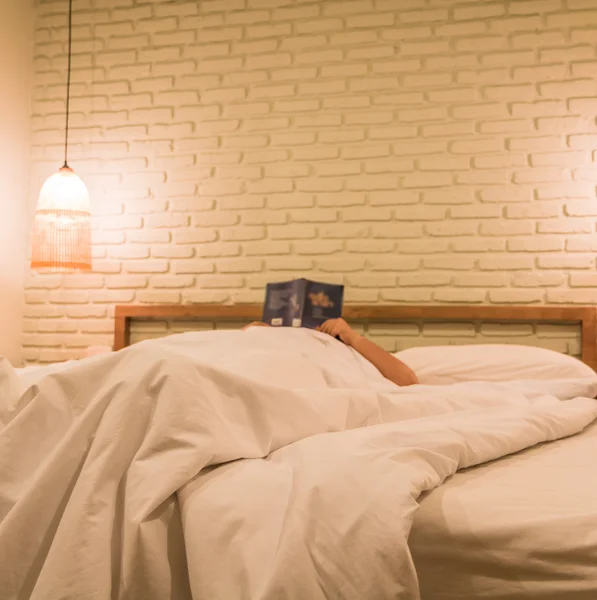 Жінка в ліжку читає книгу — стокове фото