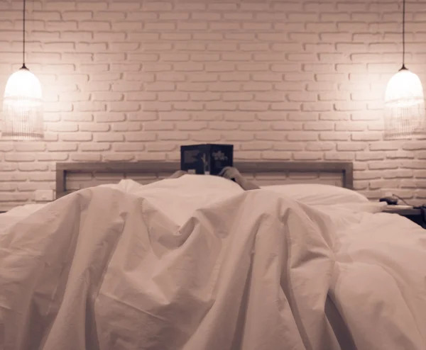 Vrouw in bed lezen van boek — Stockfoto