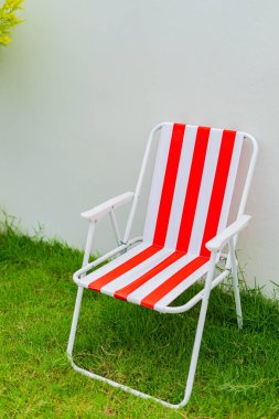  Plaj sandalyeleri çimenlerin üzerinde ve evin bahçesinde beyaz beton bir duvara yaslanmış..