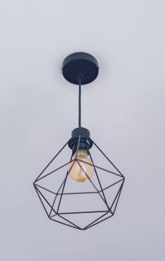 Beyaz tavanın altında bir lamba asılı..