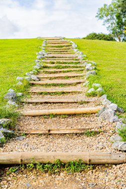 A path up the mountain through green grass and beautiful sky.