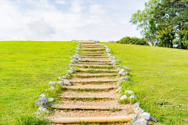 A path up the mountain through green grass and beautiful sky.