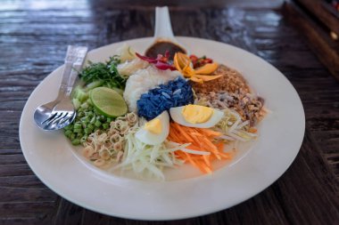 Meşhur yerel yiyecekler. Adı Khao Yum, Kaw yum, Tayland 'ın güneyindeki yemek tarzı. Tayland pirinci ve sebzelerin karışımı yumurta, kızarmış karides ve tuzlu sosla birlikte yenir..