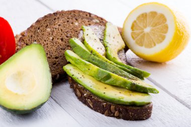 Lezzetli avokado sandviç koyu siyah ekmek üzerinde.