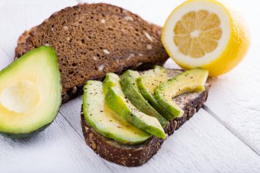 Koyu siyah ekmek üzerinde avokado sandviç.